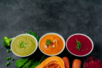 Set of vegetable soups. Broccoli, spinach, green peas soup. Pumpkin and carrot soup. Beetroot and carrot soup on a stone background  with copy space for your text