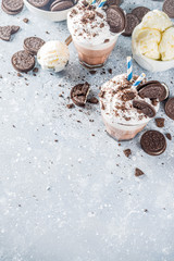 Coffee mocha milkshake with cookies and cream. Ice cream and chocolate cookies sweet latte cocktail. On gray concrete table, with spoon and cup of vanilla ice cream. Copy space