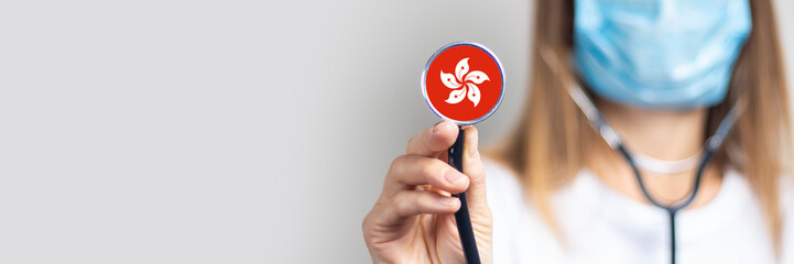 female doctor in a medical mask holds a stethoscope on a light background. Added flag of Hong Kong....