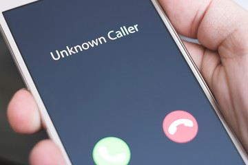 Unknown caller. A man holds a phone in his hand and thinks to end the call. Incoming from an unknown number at night. Incognito or anonymous