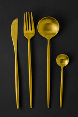 Set of golden instruments - a spoon, fork, knife, teaspoon.