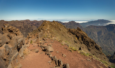 Aerial view of the National Park Caldera de Taburiente, volcanic crater seen from mountain peak of Roque de los Muchachos Viewpoint. Tenerife and El Hierro above the clouds. La Palma, Spain