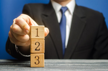 Businessman puts wooden blocks with the number 1 2 3. Task list. Alternate items and conditions for...