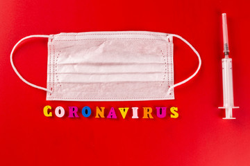 Coronavirus word made of colourful letters on red background . The inscription on medical protective mask coronavirus.