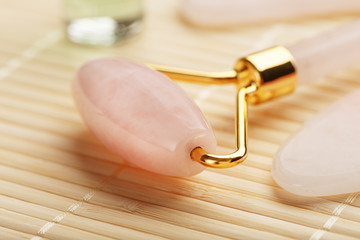 Gua sha massage made of natural rose Quartz-roller, jade stone and oil, on a bamboo background for...