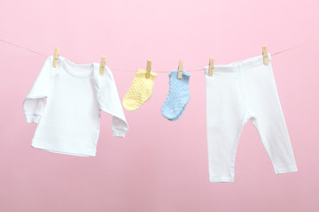 Baby clothes on a rope on a colored background. The concept of washing baby clothes.