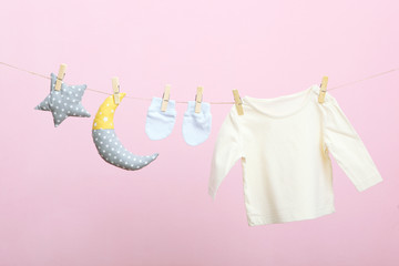 Baby clothes on a rope on a colored background. The concept of washing baby clothes.