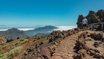 Obraz premium Aerial view of the National Park Caldera de Taburiente, volcanic crater seen from mountain peak of Roque de los Muchachos Viewpoint. El Hierro on horizon line above the clouds. La Palma, Spain