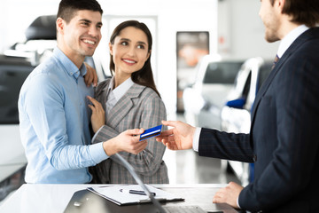 Couple Buying Car Giving Credit Card To Seller