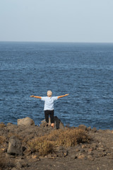 Fototapeta na wymiar Exercise, yoga to enhance the health of older people. The opportunity to live longer with a healthy lifestyle. Old woman on the ocean raised her arms up.