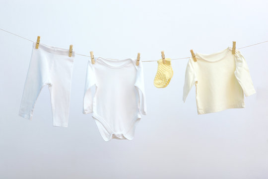 Baby clothes on a rope on a colored background. The concept of washing baby clothes.
