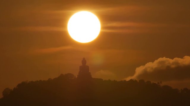 hue sunset over  silhouette Phuket big buddha statue on hilltop with many big trees high mountain in the beautiful evening colourful  orange twilight sky,moving cloud,  attraction tourist photo spot