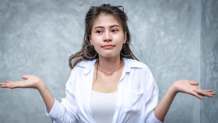 Asian beautiful woman with yellow skin, long black hair, wearing a white shirt, jeans showing her emotions.  Cement wall background-01