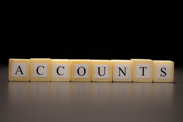 The word ACCOUNTS written on wooden cubes, isolated on a black background...