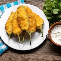 Mexican jalapeno poppers stuffed with cheese and breaded on wooden background
