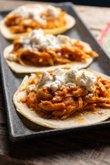 Mexican chicken tinga tacos with chipotle sauce on wooden background