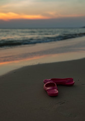 pink rubber shoes by the sea against the sunset in Thailand