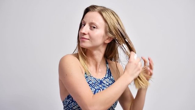 Woman with wet hair is applying on hair mousse.