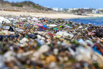 Closeup plastic trash on the sandy beach of a tropical sea