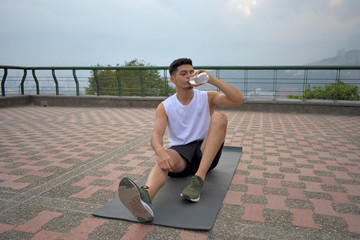 Joven hombre latina tomando agua en una sesion de deporte