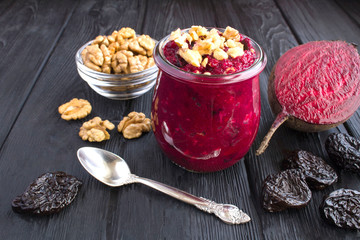 Smoothies or puree with beet, walnuts and prunes in the small glass jar on the black wooden  background. Closeup.