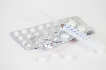 Tablets, capsules, medications, a thermometer and a syringe lie on a white background. Medical means of fighting viruses, coronavirus, covid 19