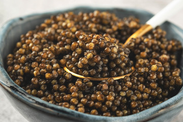 black caviar in a bowl on a golden spoon