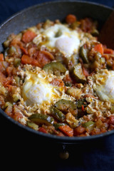 Shakshuka in a pan, with seasonal vegetables and eggs. Selective focus.