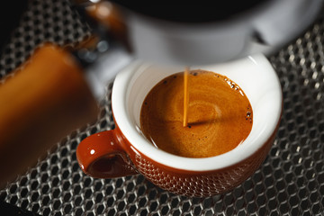 Brew espresso from a coffee machine into a brown porcelain cup