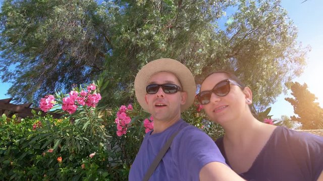 Happy couple taking a selfie and sending greetings in tropical resort in 4k slow motion 60fps