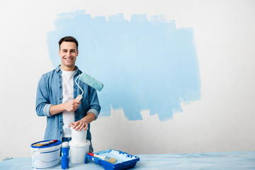 Smiling young man with tools and paint - obrazy, fototapety, plakaty