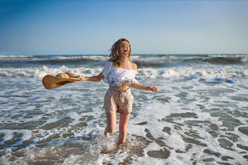 Naklejka premium Cheerful girl in glasses and a hat on the seashore