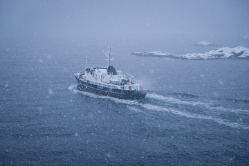 Fishing ship on the way to the ocean. Traditional cod fish season lasts during winter period. Located in beautiful lofoten islands archipelago. Fish industry behind the arctic circle. 