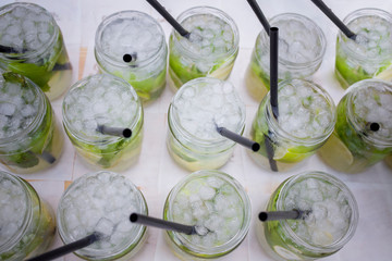 Full fresh made mojito glasses with green leaves, sugar and lime