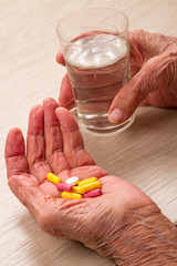 Old woman with pills in the palm of your hand