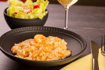 plate of shrimp risotto, lettuce salad and cherry tomatoes and a glass of white wine