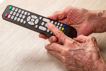 Оld woman with remote control TV