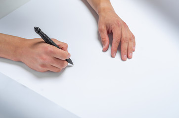 Male hand writes a black pen on white paper