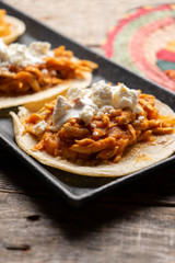 Mexican chicken tinga tacos with chipotle sauce on wooden background