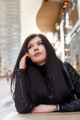 Naklejka premium Portrait of a girl in the city. Beautiful brunette in the city streets. Stylish woman travels the cities of Europe.