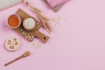 Bowl of dry oatmeal with honey and ears of wheat on light background. Healthy skin, facial and body care.