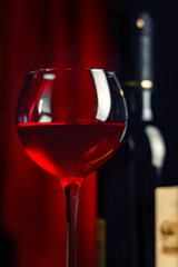 Wine. A glass and a bottle of red wine.. Red wine on a dark red background