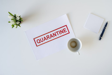 Abandoned workplace of a sick employee in the office due to coronavirus and quarantine with a cup of finished coffee. Worldwide pandemic concept