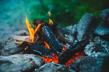 Vivid smoldered firewoods burned in fire close-up. Atmospheric warm background with orange flame of...