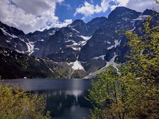 View of green trees, Morskie Oko Lake and Tatra Mountains in spring