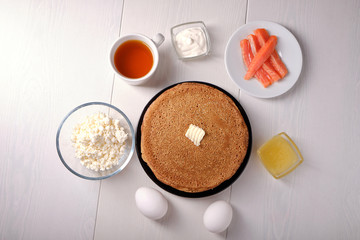Obraz na płótnie Canvas Plate with pancakes on a white table, honey, sour cream