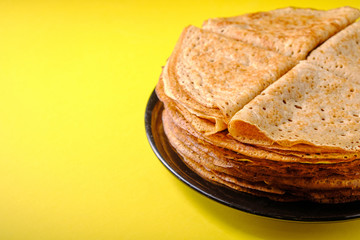 Plate with pancakes on a yellow background, side view