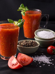 tomato juice in a glass on a black background.