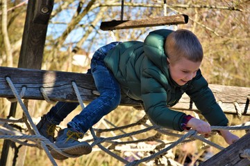 boy on the playground climbs the rope
