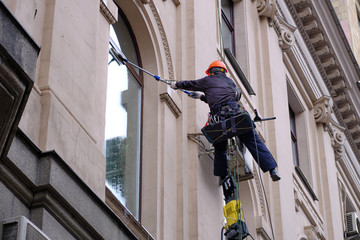 Worker mops up windows, bottom view, safety ropes